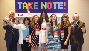 Court reporting students and the NCRA president and CEO stand in front of the Take Note campaign sign