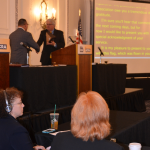 NCRA Executive Director and CEO Mike Nelson, CAE, presents 2015-2016 NCRA President Steve Zinone, RPR, with an American flag that was flown over the U.S. Capitol, during the Annual Business Meeting.