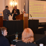 NCRA Executive Director and CEO Mike Nelson, CAE, presents 2015-2016 NCRA President Steve Zinone, RPR, with an American flag that was flown over the U.S. Capitol, during the Annual Business Meeting. 