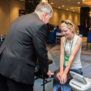 A man in a suit shows a steno machine to a reporter at the Expo Hall