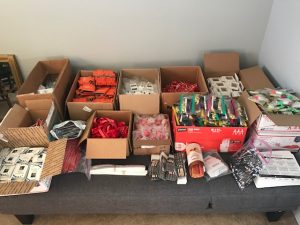 Various-sized boxes on a table, each filled with a different small item such as coozies, lanyards, and chocolates