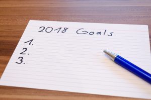 pen and index card with "2018 goals" written at the top and a list