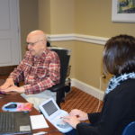 Volunteer interviewer JoAnne Luciano talks with U.S. Veteran James Andreatta, who served during the Cold War, as Christine Slezosky, a captioner from Chambersburg, Pa., transcribes his story, during a VHP event held at the Ginger Cove Retirement Community in Annapolis, Md.