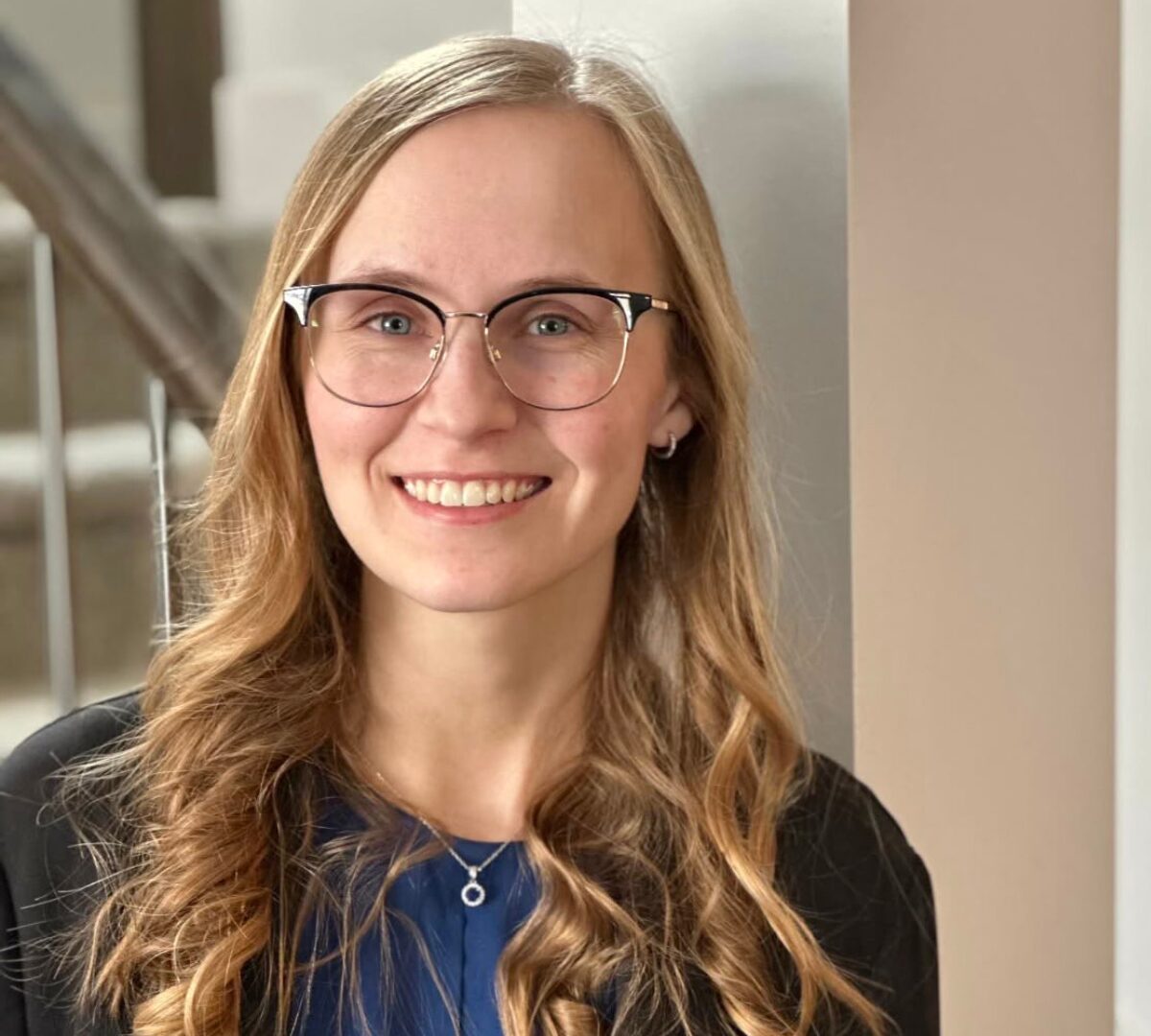 A woman with long blonde hair, wearing glasses