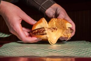 Hands holding a cheeseburger cut in half