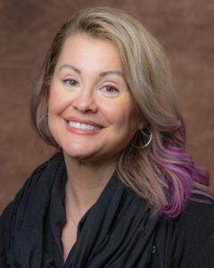 Professional headshot of blonde woman smiling at a camera