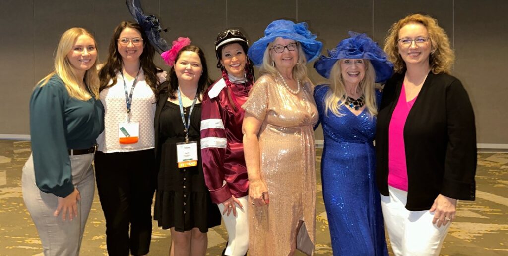 Women in festive fascinator hats posing together and smiling