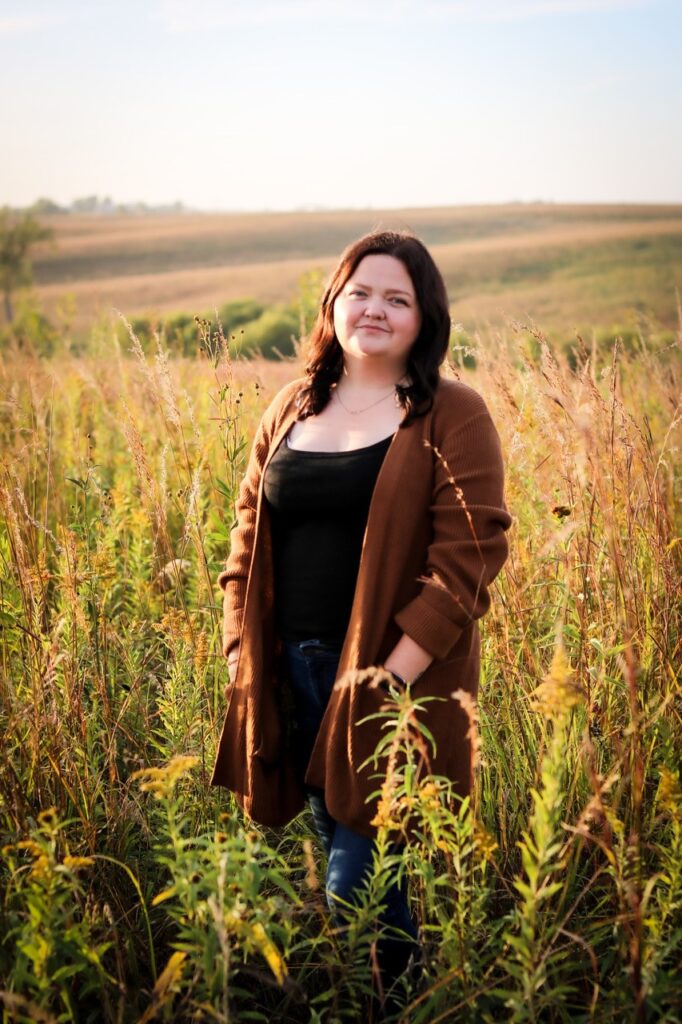 Woman standing in a field smiling at the cameral