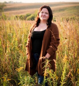 Woman standing in a field smiling at the cameral