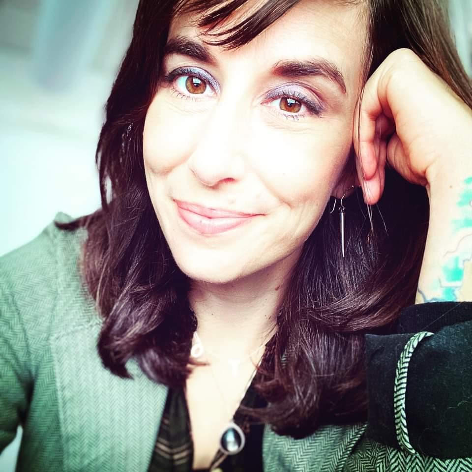 Brunette woman leaning on her hand and smiling at the camera