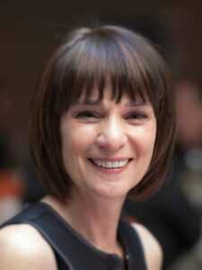 Headshot of woman with dark hair and bang smiling at the camera