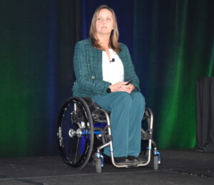 A woman sitting in a wheelchair presenting on a stage