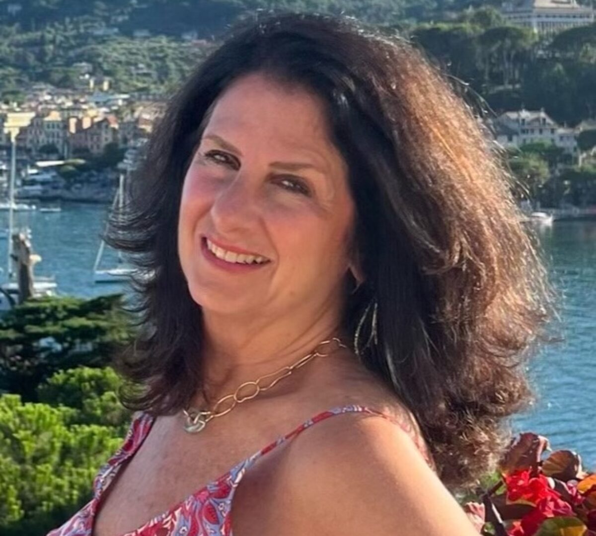 Brunette smiling at the camera above a bay with sailboats