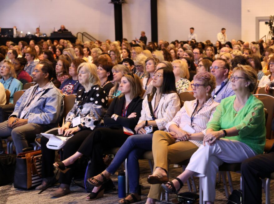 A crowd of people sitting in an auditorium looking toward the stage