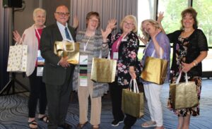 People standing, holding gold bags and making a silly pose for the camera