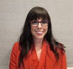 Headshot of woman in glasses and a red suit smiling at the camera