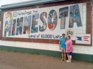 A man and a woman posing in front of a billboard