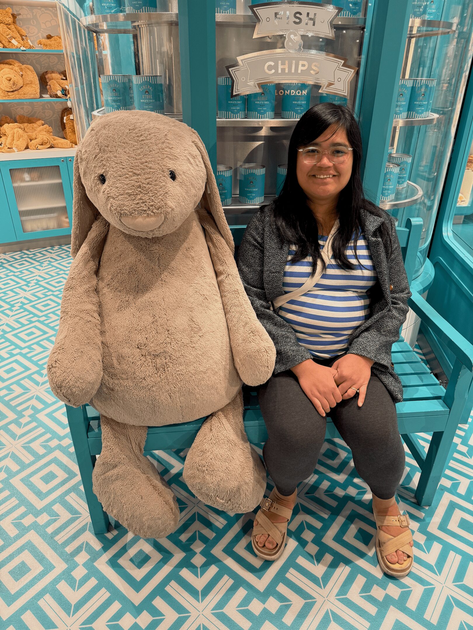 Woman sitting on a bench next to a giant stuffed rabbit