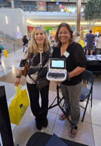 Two women posing for the camera and holding a steno machine
