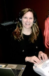 A woman smiling at the camera and writing on a steno machine