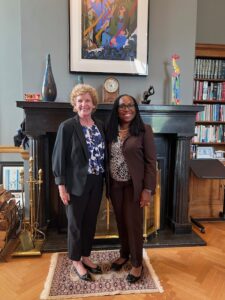 Two women posing for a picture in front of a fireplace