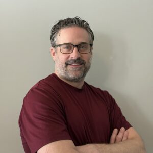 Professional headshot of a man in a beard and glasses