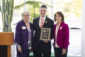 A man receiving an award from two women