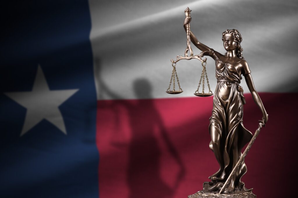 Gold statue of Lady Justice against the Texas flag
