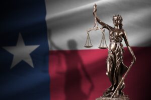 Gold statue of Lady Justice against the Texas flag