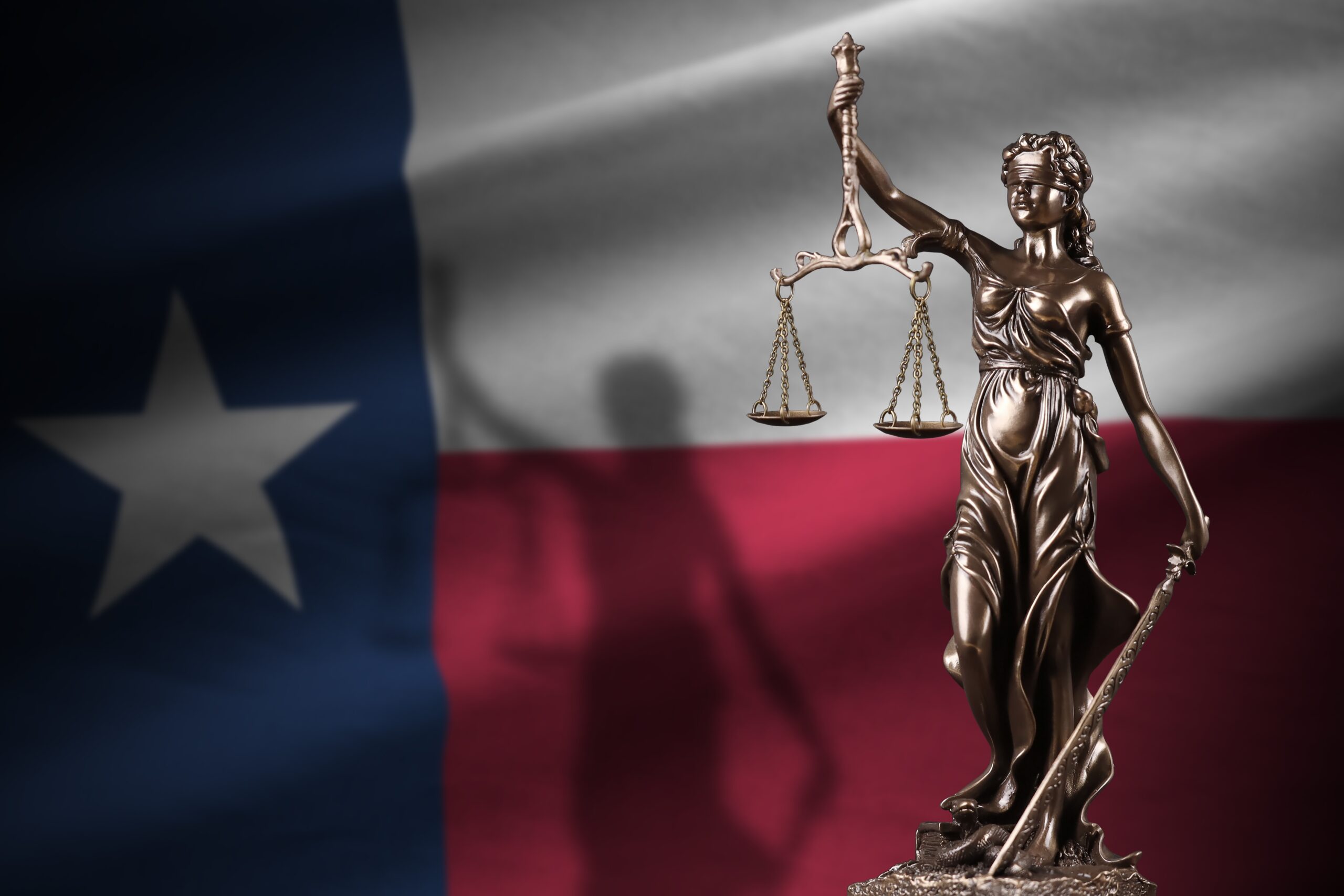 Gold statue of Lady Justice against the Texas flag